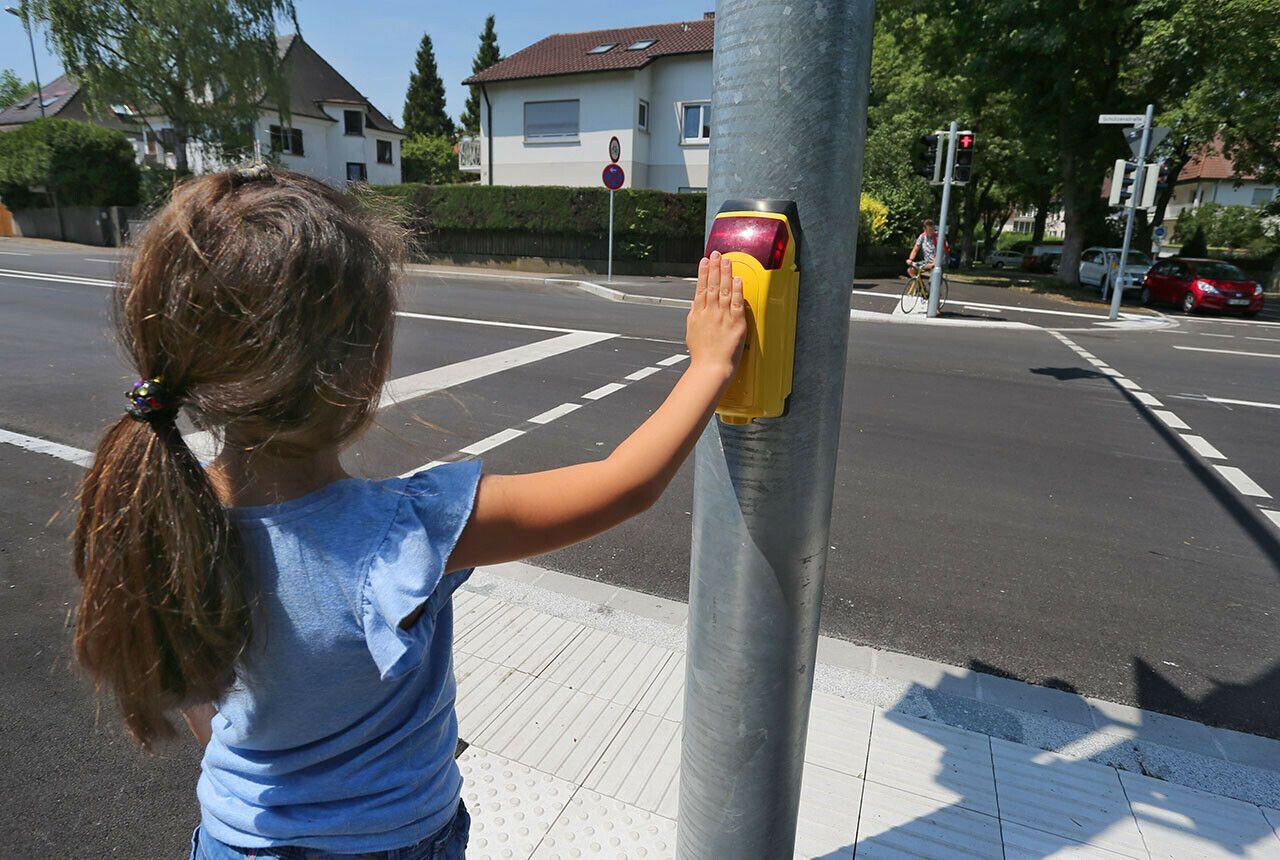 Kind steht an Ampel und betätigt Knopf